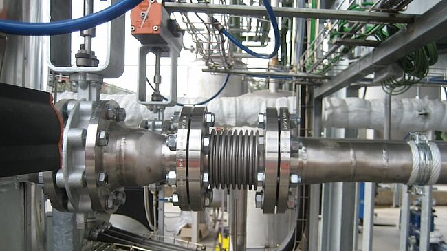 Edelstahl-Kompensator in einer industriellen Rohrleitung zur Aufnahme von Bewegungen und Druckveränderungen